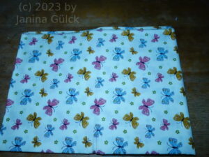 cream colored fabric with butterflies in pink, blue and yellow, right size for Barbie